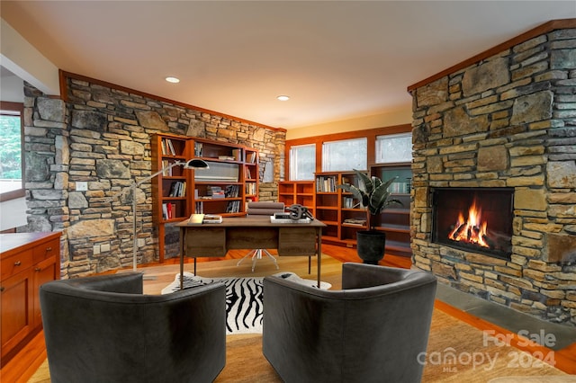 home office featuring a stone fireplace and light hardwood / wood-style floors