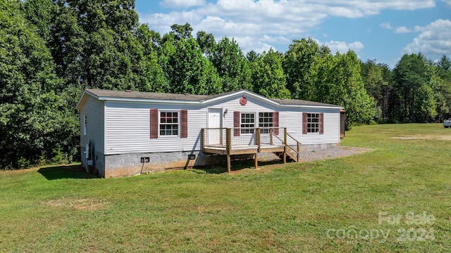 manufactured / mobile home featuring a wooden deck and a front lawn