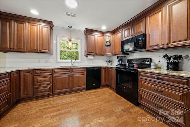 kitchen with light hardwood / wood-style flooring, decorative light fixtures, black appliances, sink, and light stone countertops