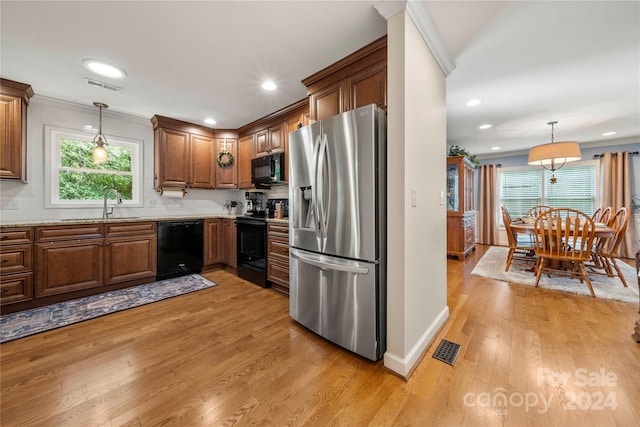 kitchen featuring black appliances, sink, decorative light fixtures, and light hardwood / wood-style floors