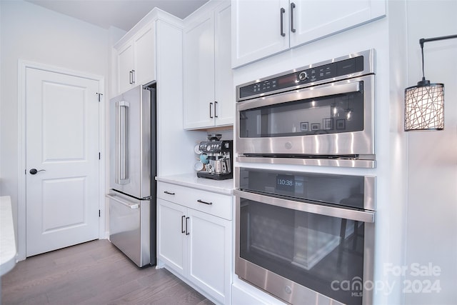 kitchen with white cabinets, appliances with stainless steel finishes, and light hardwood / wood-style floors