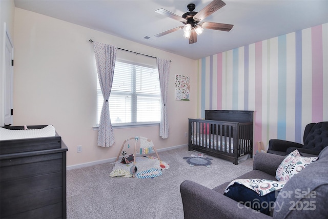 bedroom featuring a crib, light colored carpet, and ceiling fan