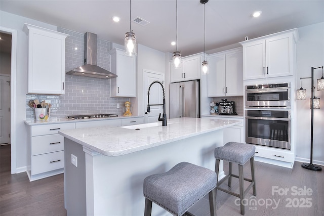 kitchen with white cabinetry, appliances with stainless steel finishes, sink, and wall chimney exhaust hood