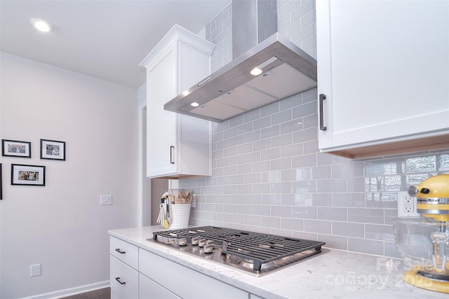 kitchen featuring stainless steel gas stovetop, tasteful backsplash, white cabinets, and wall chimney exhaust hood