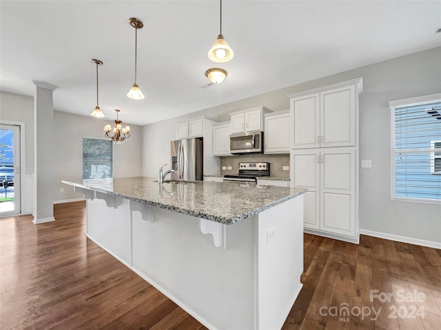 kitchen featuring appliances with stainless steel finishes, white cabinets, dark wood-type flooring, and a kitchen breakfast bar