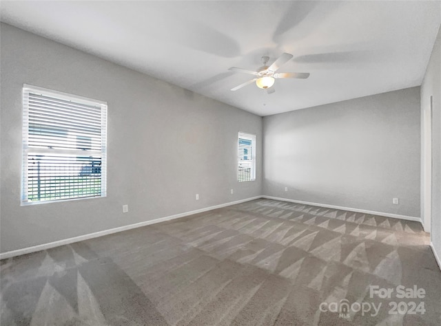 carpeted empty room with a wealth of natural light, ceiling fan, and baseboards