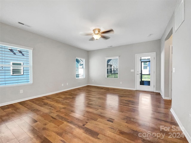 empty room featuring ceiling fan, wood finished floors, visible vents, and baseboards