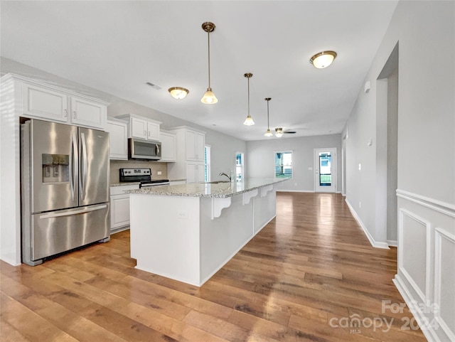 kitchen with light wood finished floors, visible vents, appliances with stainless steel finishes, white cabinets, and a sink