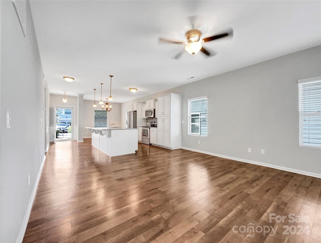 unfurnished living room featuring baseboards, a ceiling fan, and dark wood-type flooring