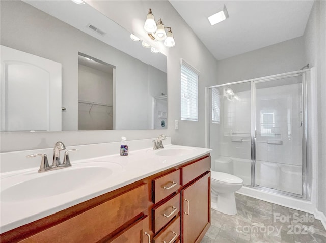 bathroom with toilet, a stall shower, a sink, and visible vents