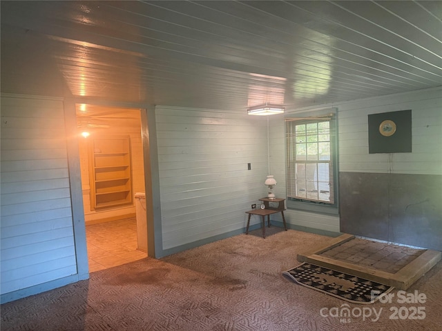 interior space featuring carpet, wooden ceiling, and wooden walls