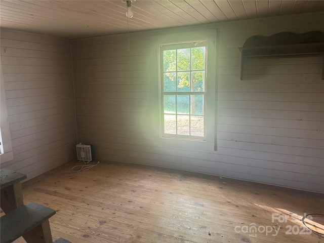 empty room with wooden walls, light hardwood / wood-style floors, and wooden ceiling