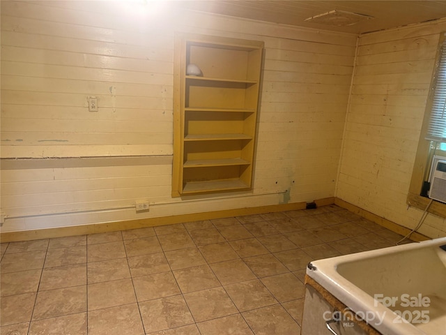 empty room with tile patterned flooring, built in shelves, and wooden walls