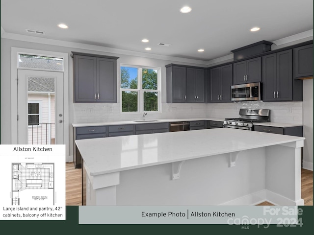 kitchen with stainless steel appliances, a center island, light wood-type flooring, and tasteful backsplash