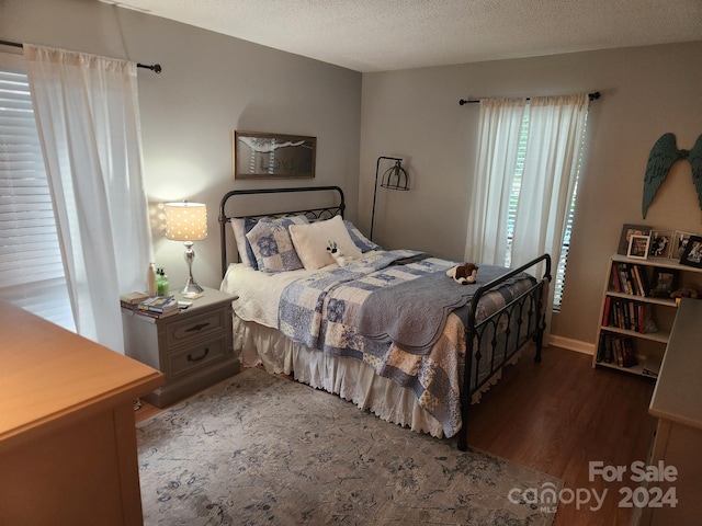 bedroom with a textured ceiling and dark wood-type flooring