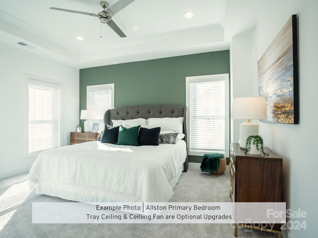 carpeted bedroom with ceiling fan and a raised ceiling