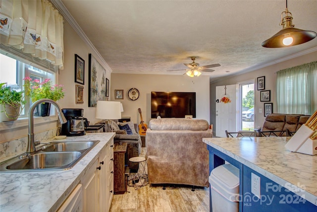 kitchen featuring a textured ceiling, decorative light fixtures, sink, ceiling fan, and light hardwood / wood-style floors