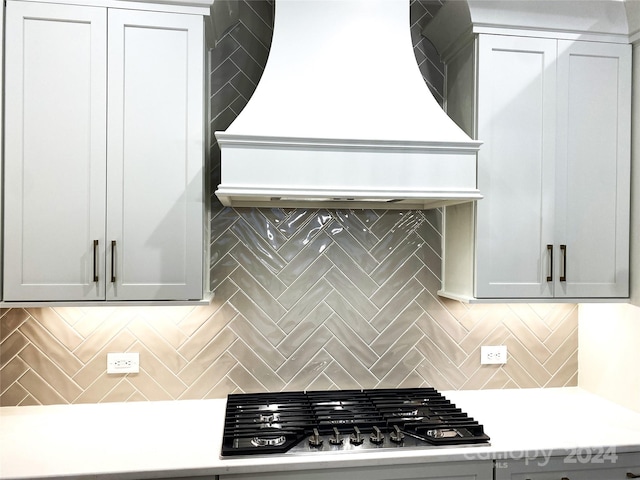 kitchen featuring backsplash, premium range hood, and stainless steel gas stovetop