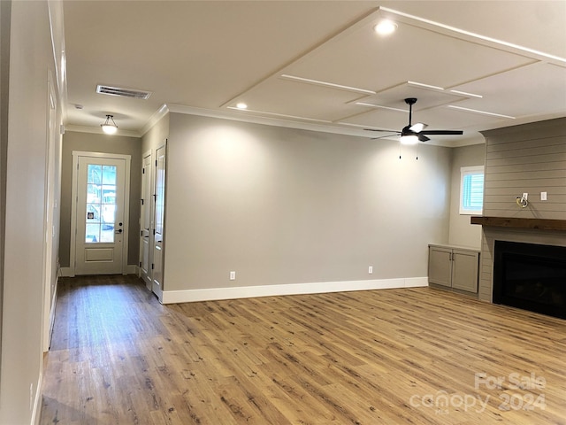 unfurnished living room with crown molding, a wealth of natural light, a fireplace, and light hardwood / wood-style floors