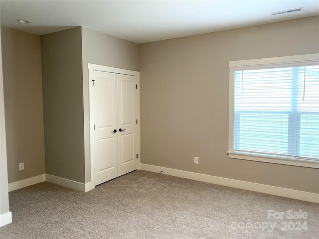 unfurnished bedroom featuring a closet and light colored carpet