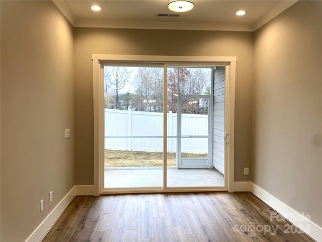 doorway with hardwood / wood-style flooring and crown molding