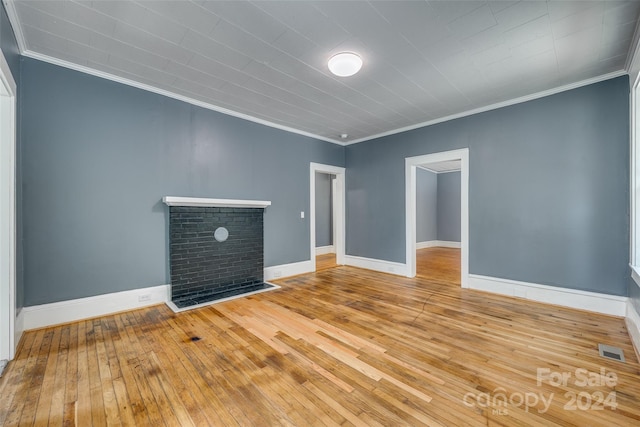 unfurnished living room with ornamental molding, a brick fireplace, and light hardwood / wood-style floors