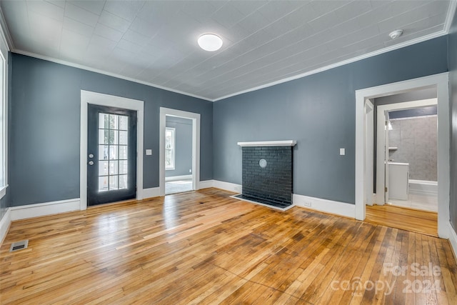 unfurnished living room featuring a brick fireplace, light hardwood / wood-style floors, and ornamental molding