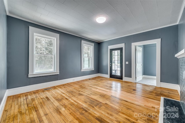 interior space featuring light wood-type flooring, crown molding, and a brick fireplace