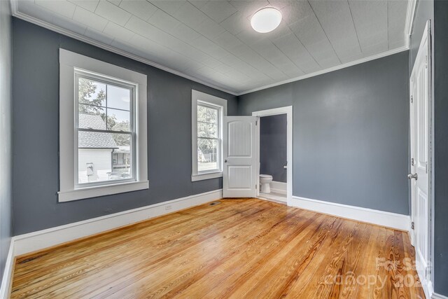 spare room featuring hardwood / wood-style flooring, ornamental molding, and a healthy amount of sunlight