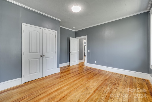 unfurnished bedroom with ornamental molding, wood-type flooring, and a closet