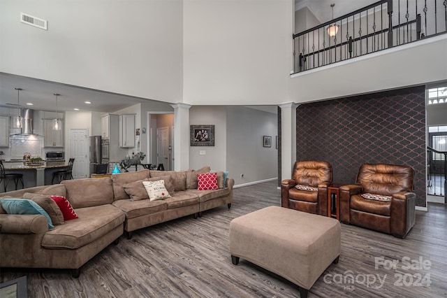 living room featuring hardwood / wood-style floors, a towering ceiling, and ornate columns