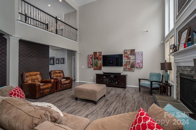 living room with hardwood / wood-style floors, a fireplace, a high ceiling, and decorative columns