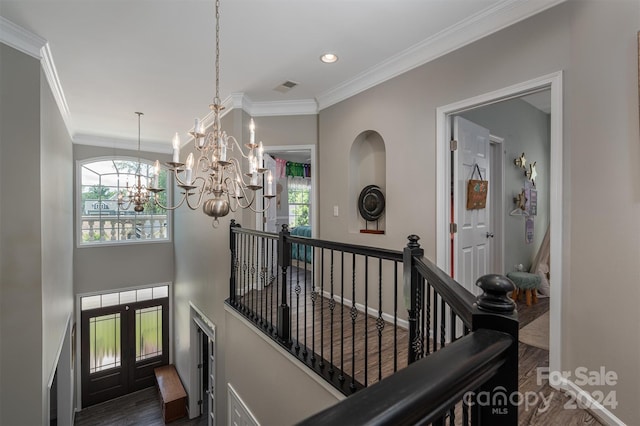 stairs with wood-type flooring, french doors, crown molding, and a chandelier