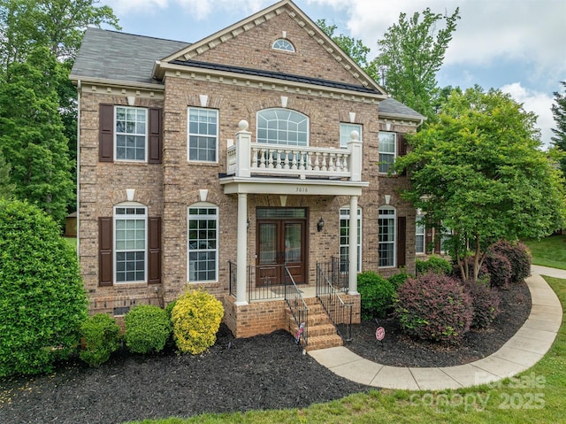 colonial-style house with a balcony, french doors, brick siding, and crawl space