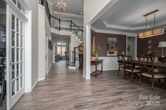 entrance foyer featuring ornamental molding, wood finished floors, stairway, french doors, and an inviting chandelier