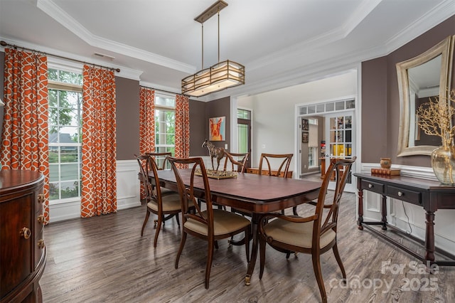 dining area featuring a decorative wall, wainscoting, wood finished floors, and ornamental molding