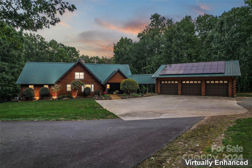 cabin featuring a garage, a lawn, and solar panels