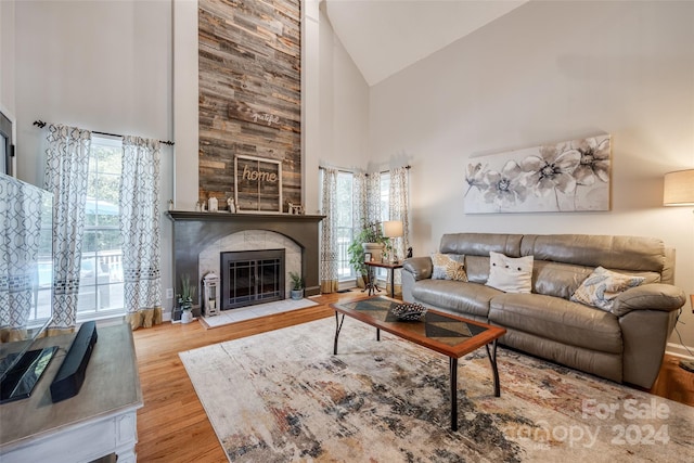 living room with high vaulted ceiling, a fireplace, and light hardwood / wood-style floors