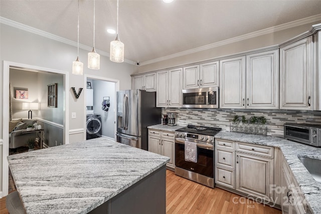 kitchen with light wood-type flooring, ornamental molding, backsplash, appliances with stainless steel finishes, and washer / clothes dryer