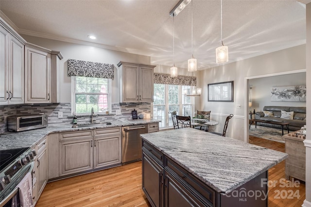 kitchen featuring light hardwood / wood-style flooring, decorative light fixtures, a kitchen island, sink, and appliances with stainless steel finishes