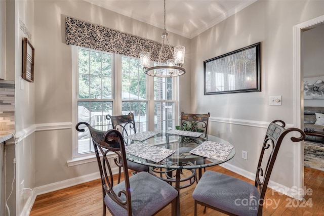 dining area with ornamental molding, light hardwood / wood-style flooring, and a notable chandelier