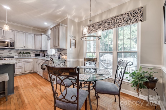 dining area featuring light wood-type flooring, crown molding, and an inviting chandelier