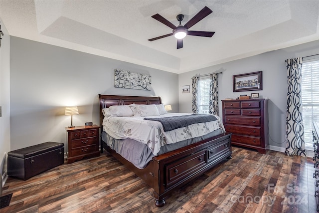 bedroom featuring a textured ceiling, a raised ceiling, ceiling fan, and dark hardwood / wood-style floors