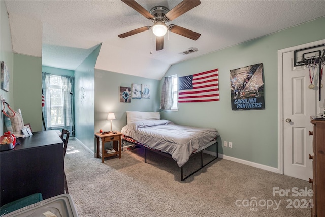 carpeted bedroom featuring vaulted ceiling, a textured ceiling, and ceiling fan