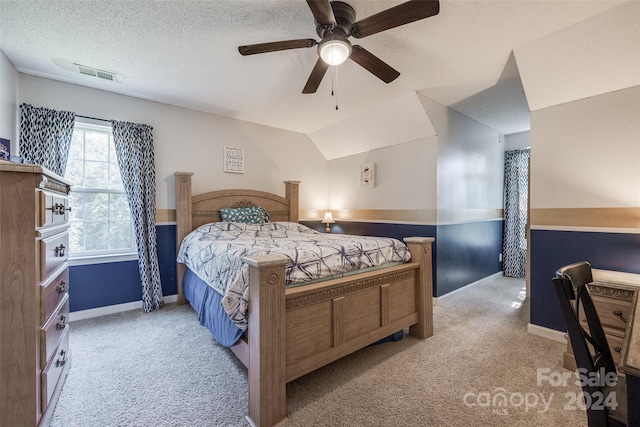 bedroom featuring light carpet, lofted ceiling, ceiling fan, and a textured ceiling