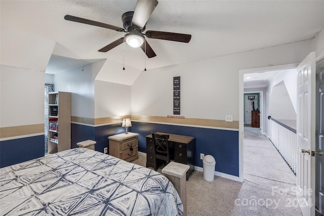 carpeted bedroom with vaulted ceiling, a textured ceiling, and ceiling fan