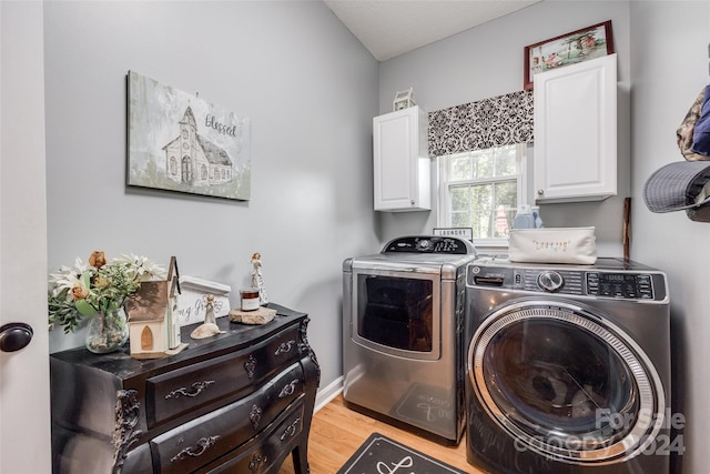 laundry area with cabinets, separate washer and dryer, and light wood-type flooring