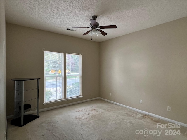 interior space featuring ceiling fan, light colored carpet, and a textured ceiling