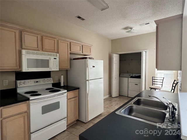 kitchen with white appliances, washing machine and clothes dryer, light brown cabinetry, and sink