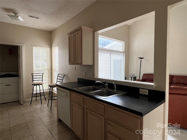 kitchen with a textured ceiling, dishwasher, sink, and light tile patterned flooring